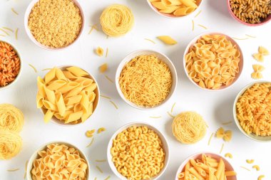 Beyaz arka planda farklı çiğ makarnalar.