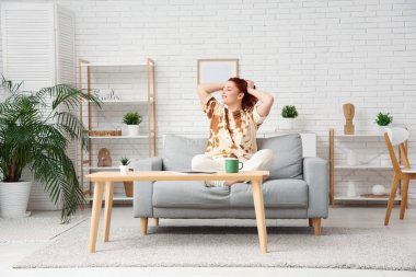 evde bir kanepede oturan genç bir kadın