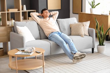 Evde koltukta oturan genç adam