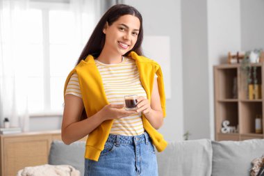 Evinde bir fincan sıcak kahveyle güzel genç bir bayan.