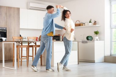Happy young beautiful couple dancing in kitchen at home