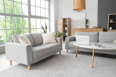 Masada gri kanepeler ve dizüstü bilgisayarlı şık bir oturma odası.