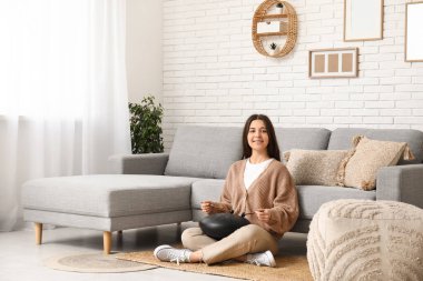 Oturma odasındaki kanepenin yanında glukofon çalan genç bir kadın.