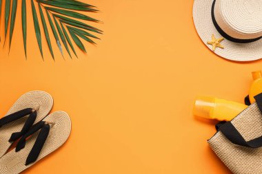 Turuncu arka planda plaj aksesuarları ve güneş kremi şişelerinden yapılmış çerçeve