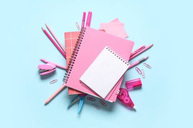 Mavi arkaplanda farklı kırtasiye malzemesi olan boş bir defter