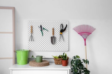 Tahtası, çekmecesi, bahçe aletleri ve bitkileri olan atölyenin içi.