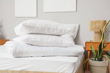 Aydınlık odada beyaz yastıklar ve katlanmış battaniyeler.