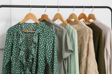 Soyunma odasındaki beyaz duvarın yanındaki kıyafetlerle doldur. Yakın çekim.