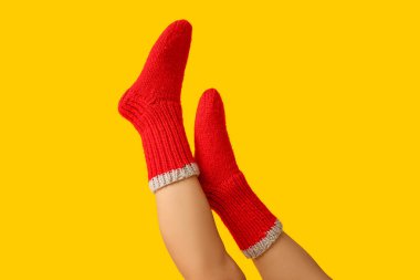 Sarı arka planda kırmızı örgü çoraplı genç bir kadın.