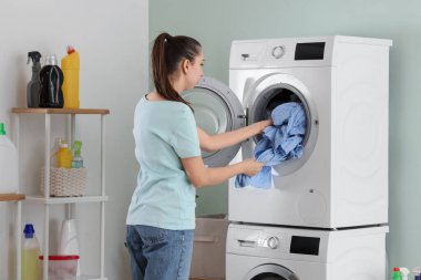 Genç kadın odada çamaşır yıkıyor.