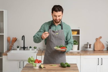 Yakışıklı adam mutfakta taze avokado, yumurta ve domates yiyor.