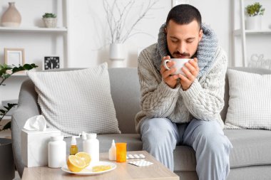 Evdeki kanepede limon çayı içen genç adam.