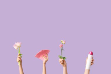 Deterjan şişesi, bez parçası ve mor arka planda gül çiçekleri olan birçok kadın eli.