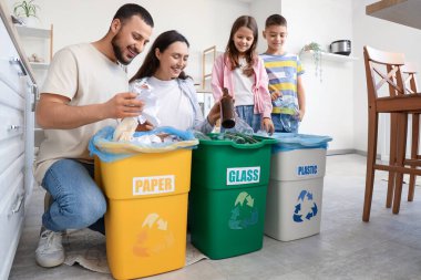 Mutfaktaki çöpleri ayıran konteynırları olan bir aile. Küresel Geri Dönüşüm Günü