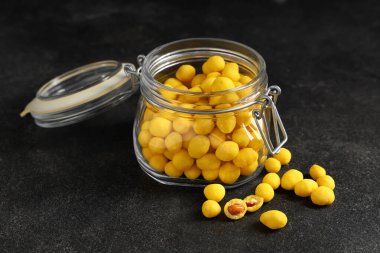 Siyah arka planda peynir kaplı fıstık kavanozu.