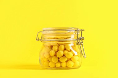 Sarı arka planda peynir kaplı fıstık kavanozu.