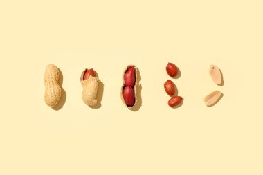 Sarı arka planda soyulmamış ve soyulmamış fıstıklar.