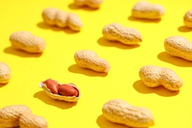 Sarı arka planda birçok soyulmamış fıstık, yakın plan.