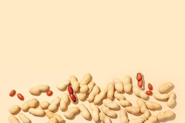 Bej arka planda soyulmamış ve soyulmamış fıstıklar.