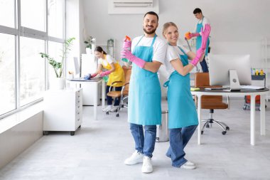 Ofisi temizleyen lastik eldivenli genç hademeler.