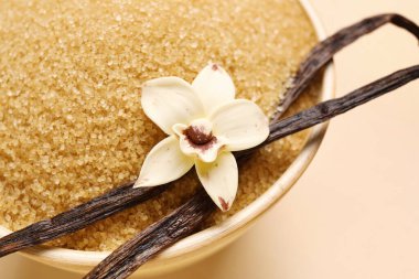 Kapsüllü vanilya şekeri ve bej arka planda çiçek, yakın plan.