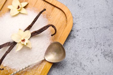 Gri arka planda çiçek ve kapsüllü ahşap tahta vanilya şekeri