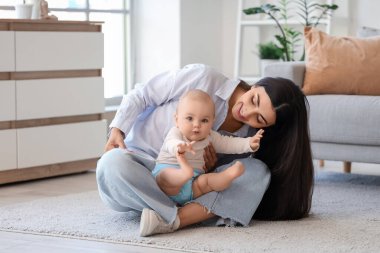 Genç, mutlu bir anne ve tatlı küçük kızı evde yerde oturuyor.