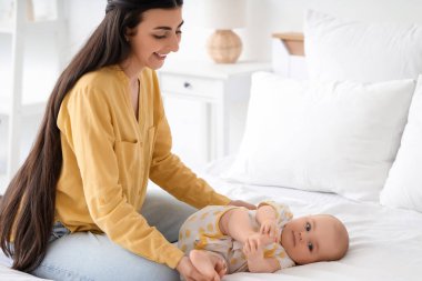 Genç, mutlu bir anne ve tatlı küçük kızı evdeki beşiğin yanında yatıyorlar.