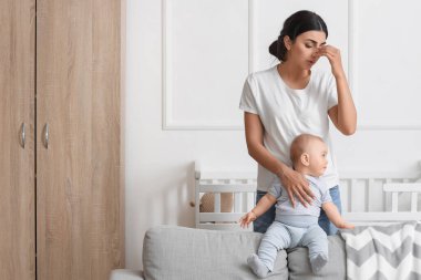 Doğum sonrası depresyon geçiren yorgun bir anne ve bebeği yatak odasında.