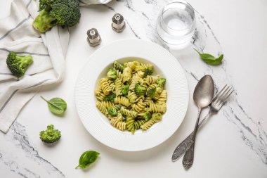 Brokolili lezzetli fusilli makarna ve beyaz arka planda bir bardak su.