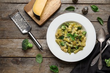 Tahta zemin üzerinde brokoli ve fesleğen yapraklı lezzetli fusilli makarna.
