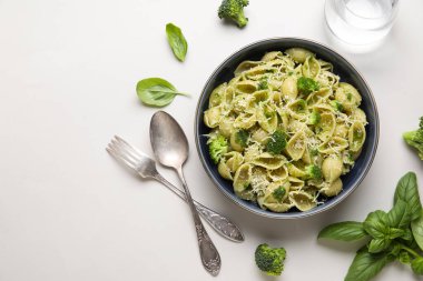 Beyaz arka planda brokoli, peynir ve fesleğen yapraklı bir kase lezzetli conchigile rigate makarna.