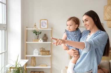 Anne ve bebeği odadaki bir şeyi işaret ediyor.