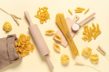 Bej arka planda farklı türde ham makarna ve oklavalı kompozisyon