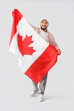 Hafif arkaplanda Kanada bayrağı taşıyan genç adam