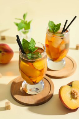 Bej arkaplanda nane ve şeftalili lezzetli buzlu çay.