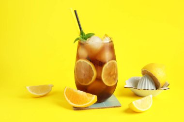 Sarı arka planda nane ve meyve sıkacağı ile Long Island buzlu çay kokteyli.