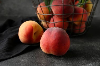 Koyu arkaplanda olgun şeftalili sepet, yakın plan.