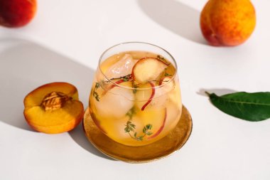 Beyaz arka planda kekik olan bir bardak taze şeftalili limonata.