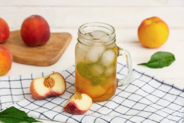 Mason kavanozu taze şeftalili limonata naneli ve beyaz ahşap arka planda meyveler.