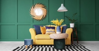 Sarı kanepeli, puflu ve aynalı şık bir oturma odası.