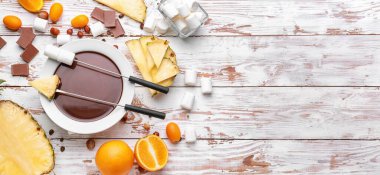 Lezzetli çikolata fondülü kase, marşmelov ve beyaz ahşap zemin üzerindeki meyveler.