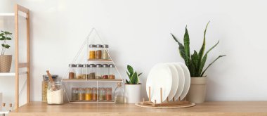 Mutfaktaki ışık duvarının yanında farklı baharat, tabak ve bitkilerle dolu raflar.