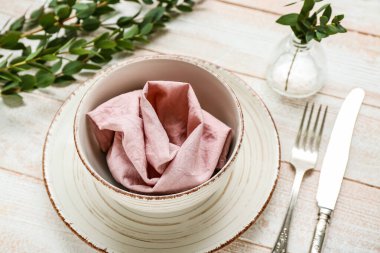 Çiçek dalları vazosu ve pembe ahşap arka planda peçeteyle güzel bir masa.