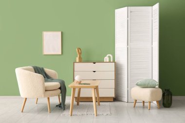 Modern oturma odası, beyaz koltuk, çekmeceler ve katlanır ekran.