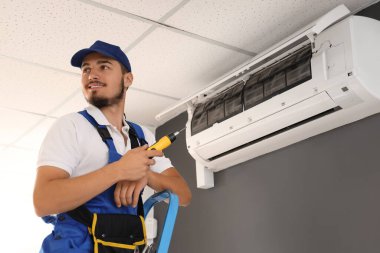 Erkek teknisyen odada klima tamir ediyor.
