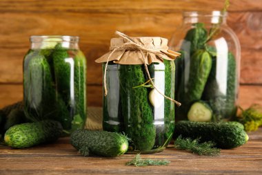 Taze ve konserve salatalıklı kavanozlar ahşap arka planda