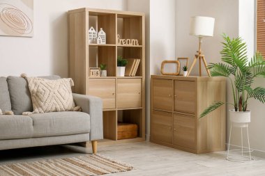 Rahat kanepesi, çiçekleri, resmi ve rafları olan modern oturma odasının içinde.