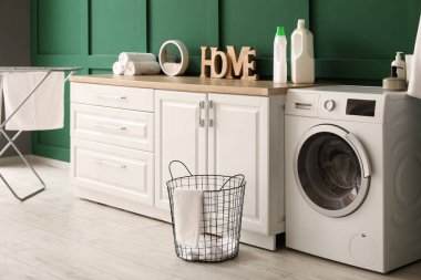 Çamaşır sepeti, çamaşır makinesi ve tezgahlı odanın içi.
