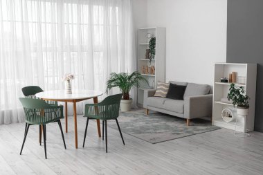 Masası, sandalyeleri, kanepesi, çiçekleri ve raf ünitesi olan modern oturma odasının içinde.